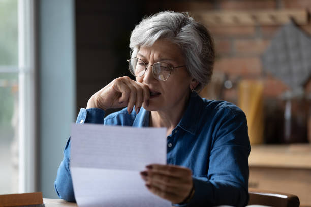 Person overwhelmed by a pile of medical paperwork on a kitchen table