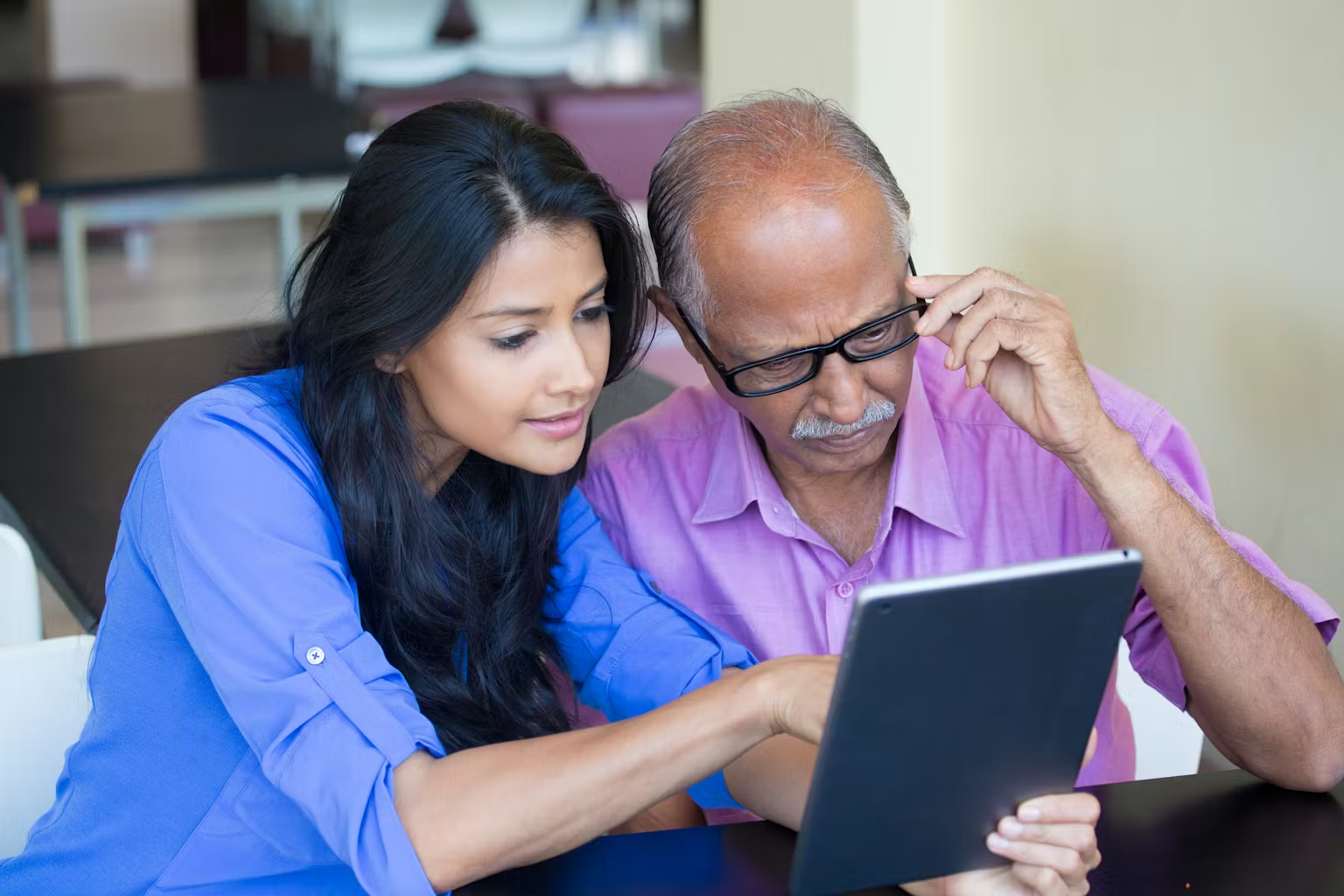 Adult daughter and elderly parent reviewing health information on a tablet at home